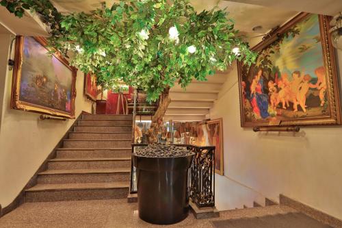 a staircase with a tree and paintings on the wall at Diamond City Hotel SHA Certified in Bangkok