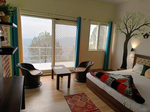 a bedroom with a bed and chairs and a large window at Joshi Holiday Home Stay in Lansdowne