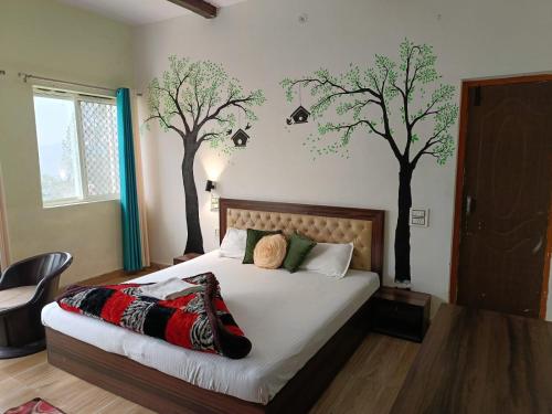 a bedroom with a bed with two trees on the wall at Joshi Holiday Home Stay in Lansdowne
