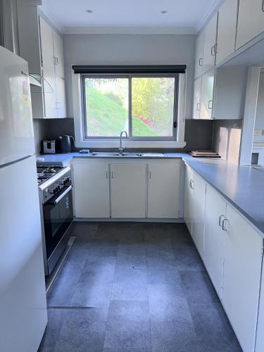 a kitchen with white cabinets and a window at Buchan Motel in Buchan