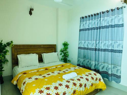 a bedroom with a bed with a yellow blanket at Hotel Nice Look in Kuākāta