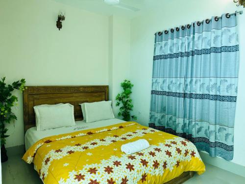 a bedroom with a bed with a yellow blanket at Hotel Nice Look in Kuākāta