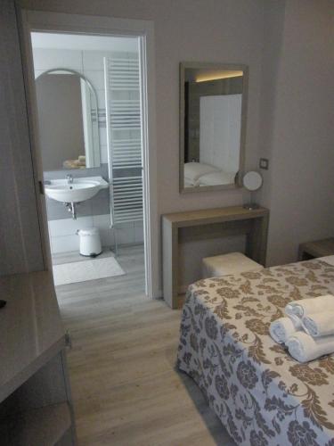 a bedroom with a bed and a sink and a mirror at Hotel Stefan Room & Breakfast in Gatteo a Mare