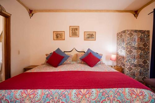 a bedroom with a large bed with red and blue pillows at Hotel Casa Blanca in Ajijic