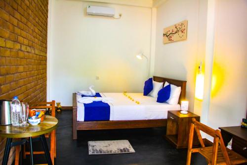 a bedroom with a bed with blue pillows and a table at Sigiriya Dream Inn in Sigiriya