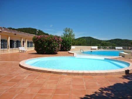 2 piscines dans une cour avec un bâtiment dans l'établissement Maison NICOLA, à Fréjus