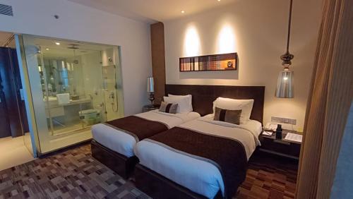 a hotel room with two beds and a shower at Pride Hotel Pune in Pune