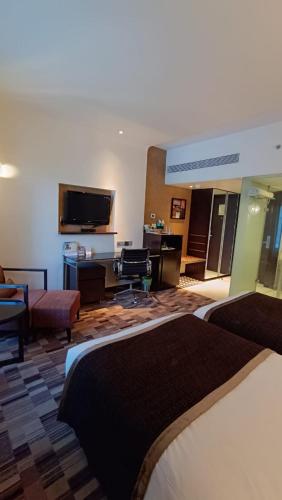 a hotel room with a bed and a flat screen tv at Pride Hotel Pune in Pune