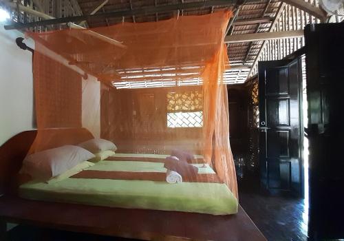 a bedroom with a bed with an orange canopy at Mutiara Beach Resort in Berakit