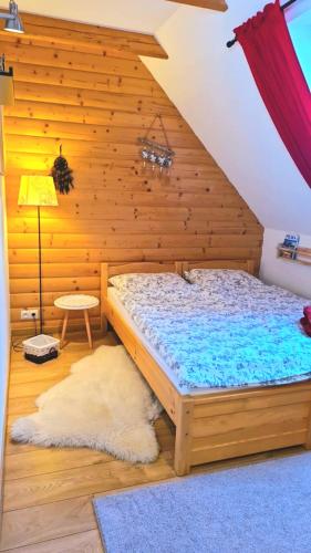 a bedroom with a bed with a wooden wall at Apartament U Moniki, nad rzeką, jacuzzi w ogrodzie in Szaflary