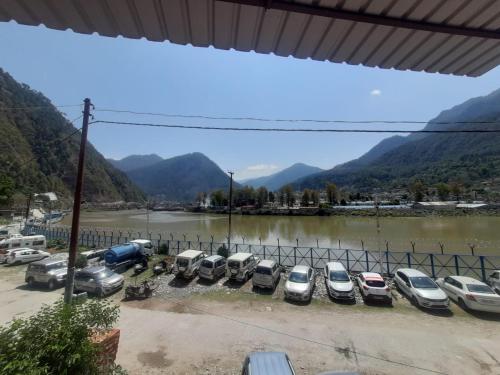 a row of cars parked in a parking lot next to a river at Mangalam Palace in Uttarkāshi