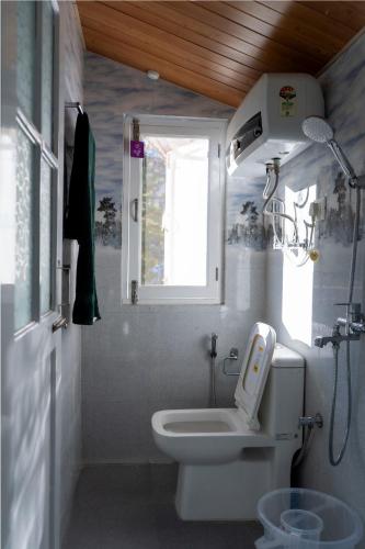 a bathroom with a toilet and a window at Solisvista Stays in Mashobra