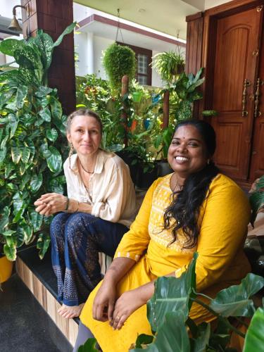 a man and a woman sitting on a porch with plants at Oyster Marris Homestays in Trivandrum