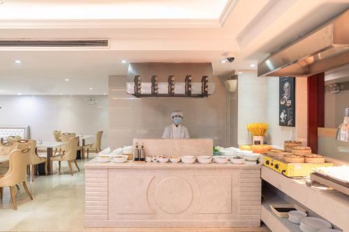 a chef wearing a mask in a restaurant kitchen at Vienna International Hotel - Shanghai Pudong Airport Free Trade Zone in Shanghai
