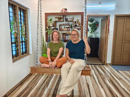 two women sitting on a porch swing at Oyster Marris Homestays in Trivandrum