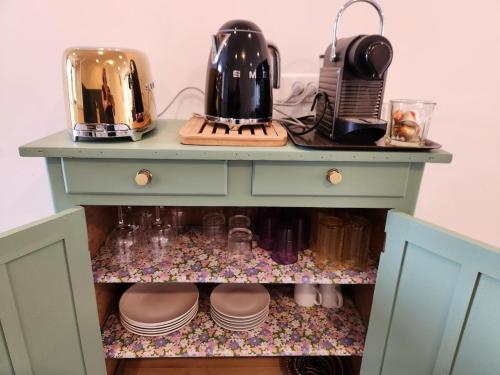a blue cabinet with two tea pots and pans on it at Cour Saint Jean in Le Neubourg