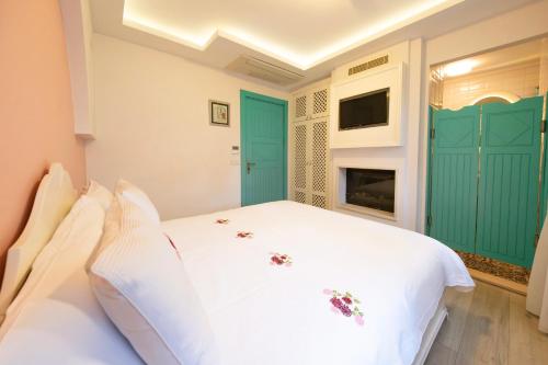 a bedroom with a white bed and a fireplace at Sigacik Gardenya Buti̇k Otel in Siğacık