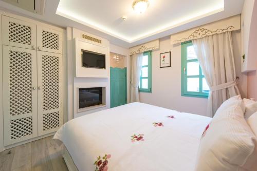 a bedroom with a white bed and a fireplace at Sigacik Gardenya Buti̇k Otel in Siğacık