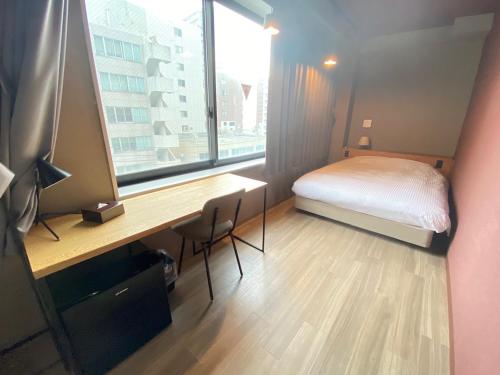 札幌市にあるWISE OWL HOSTELS SAPPOROのベッドと机と窓のある寝室