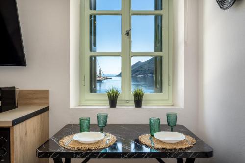 a table with two plates and a window at Agkyra Studio in Symi