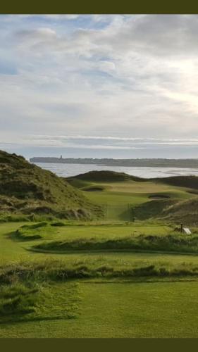 a view of a golf course with the ocean in the background at Elsie's Sea View Lodge Lahinch in Rineen