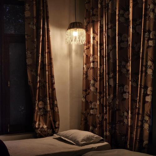 a bedroom with a bed and a chandelier and curtains at Hotel Mahadev in Dharamshala