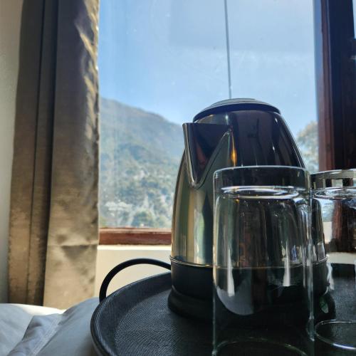 a glass appliance sitting on a table with a window at Hotel Mahadev in Dharamshala