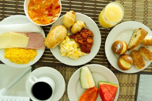 a table with plates of breakfast food and a cup of coffee at Hotel Litoral Fortaleza in Fortaleza