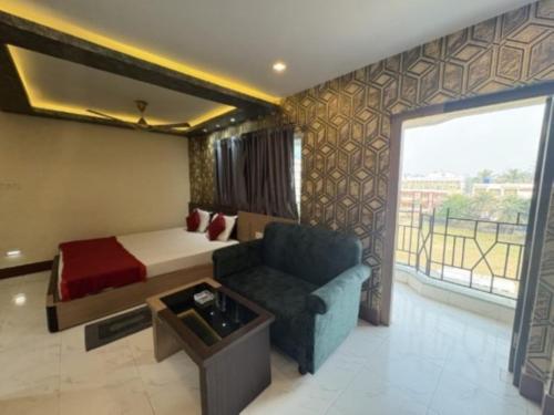 a hotel room with a bed and a couch and a window at Hotel Inn New Digha With Classic Swimming Pool in Digha
