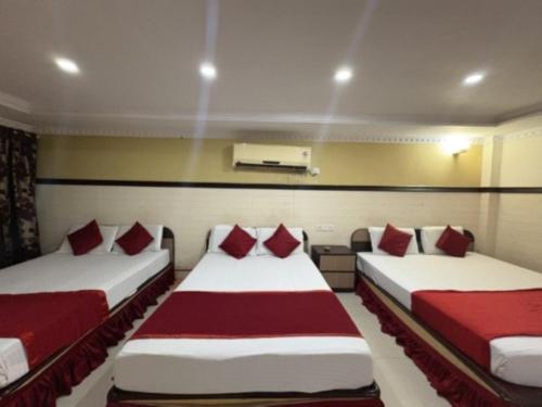 a bedroom with two beds with red and white pillows at Hotel Inn New Digha With Classic Swimming Pool in Digha