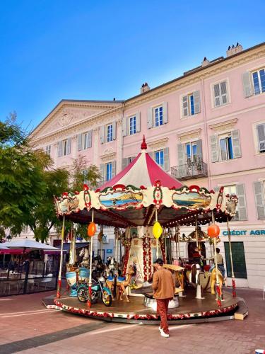 un homme debout devant un carrousel devant un bâtiment dans l'établissement Citronnier- Menton centro, à Menton