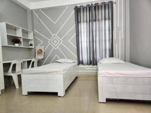 a room with two beds and a desk and a window at Akshay BnB & HomeStay in Lucknow