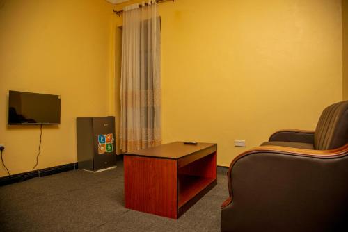 a room with a couch and a tv and a table at PK Sleek Suites in Bugembe
