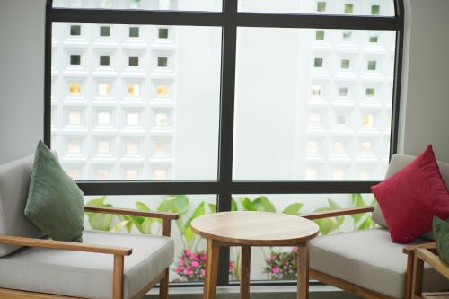 a room with two chairs and a table and a window at An Home - Garden Homestay in Plei Brel (2)