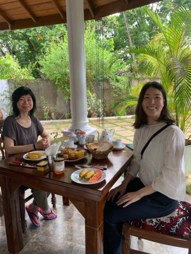 two women sitting at a table with food on it at Marigold Negombo in Negombo