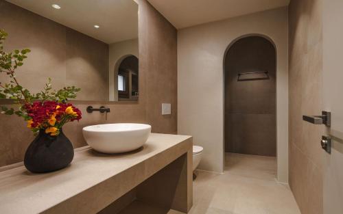 a bathroom with a sink and a vase with flowers at Theros Villas Naxos in Plaka