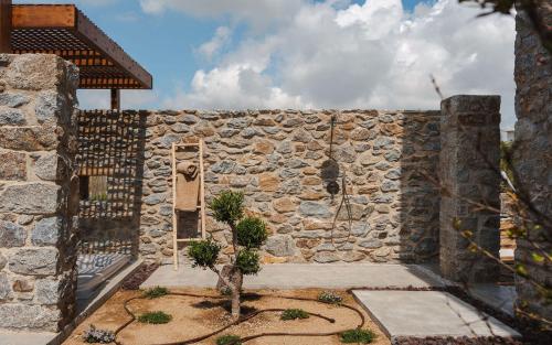 a stone wall with a tree in front of it at Theros Villas Naxos in Plaka