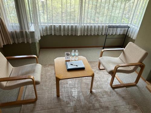 a living room with two chairs and a coffee table at Kozuka Hisanoha in Hakone