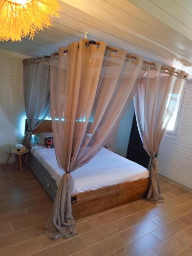 a bedroom with a canopy bed with curtains at l'Antre-Temps, maison atypique in Saint-Joseph
