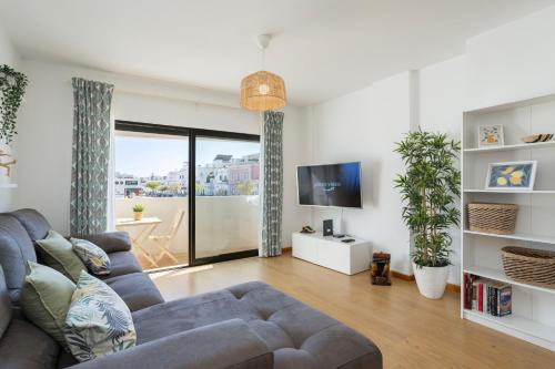 a living room with a couch and a tv at Central Olhão, 2min Island Ferry, Pool, Private Parking in Olhão