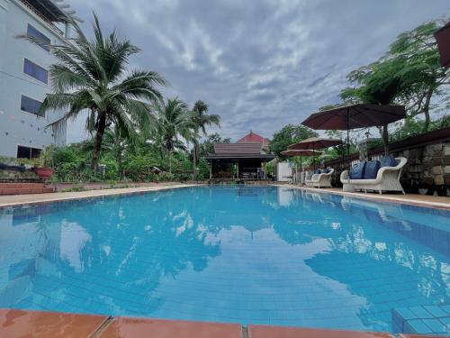 白马市Au Paradis Bleu Hotel的一个带椅子和遮阳伞的大型蓝色游泳池