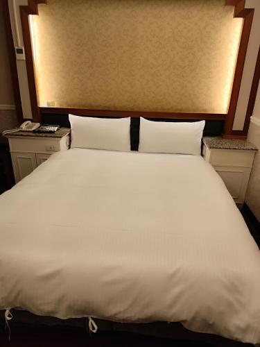 a large white bed with two night stands and two pillows at GAWA Hotel in Taipei