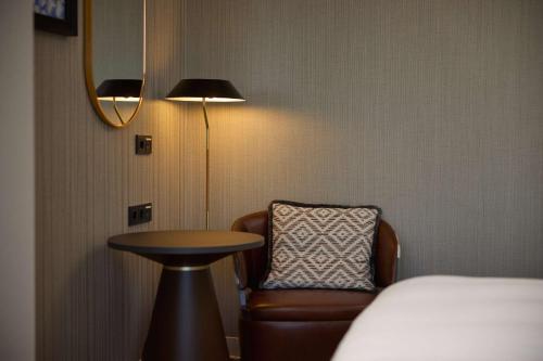 a room with a bed and a chair and a table at Haven Hotel Rotterdam, Curio Collection by Hilton in Rotterdam
