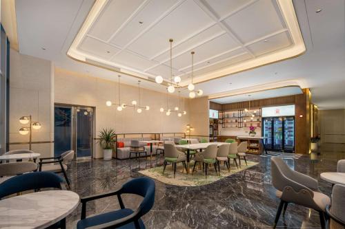 a restaurant with tables and chairs in a room at Hilton Garden Inn Suzhou Kunshan in Suzhou