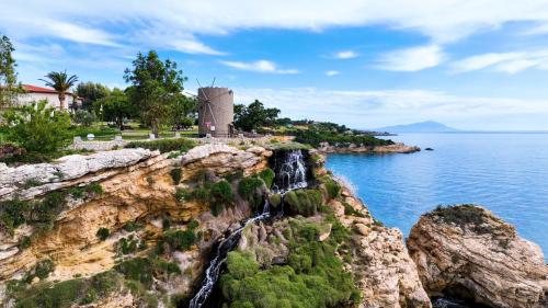 a windmill on a cliff next to the water at Club Resort Atlantis in Seferihisar