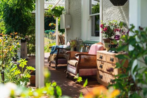 a porch with chairs and flowers on a house at Carrowmore House in Naseby