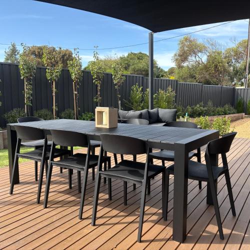a black dining table and chairs on a deck at Goolwa Beach Pavilion in Goolwa South