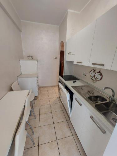 a small kitchen with white cabinets and a sink at DOMuS APA in Ladispoli