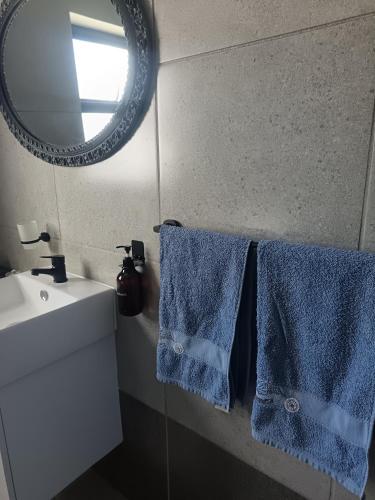 a bathroom with blue towels and a mirror and a sink at Millennial Arch in Langebaan