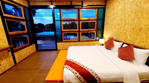 a bedroom with a bed in a room with windows at Heaven Hill Camping in Ban Thung Na